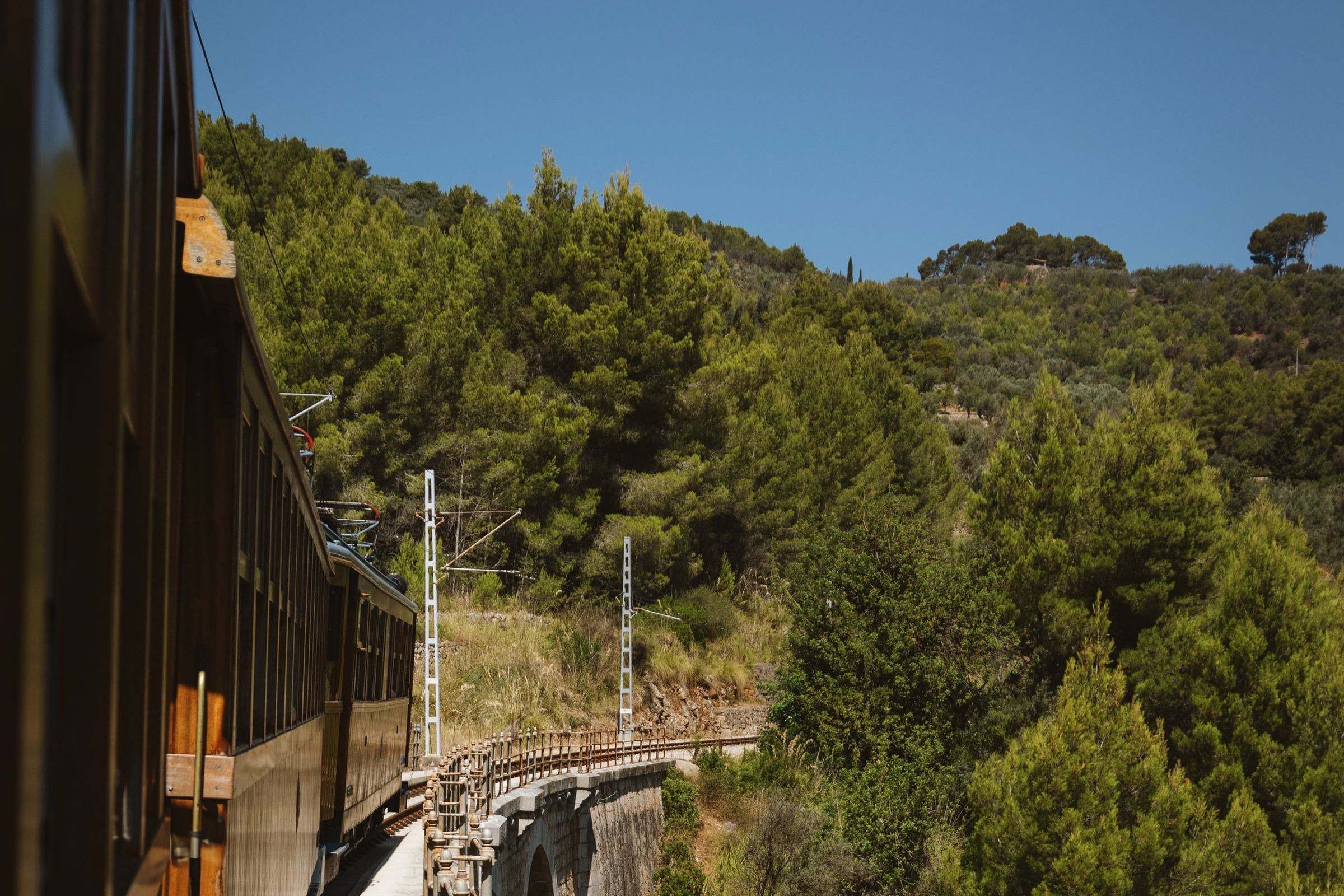 The vintage Sóller train crossing a viaduct in the mountains